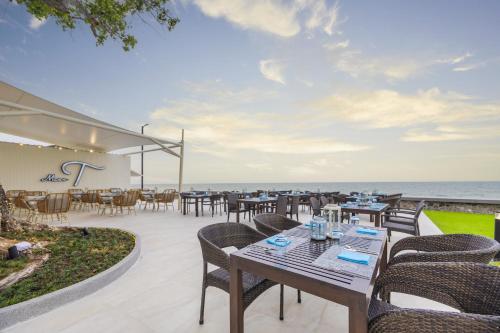 an outdoor patio with tables and chairs and the ocean at Aviyana Hua Hin in Cha Am
