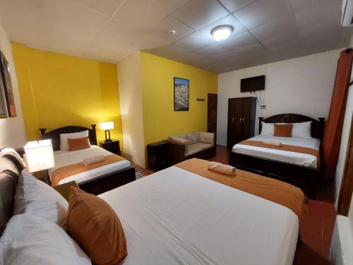 a hotel room with two beds and a couch at Hospedaje Los Lirios Chitré in Chitré