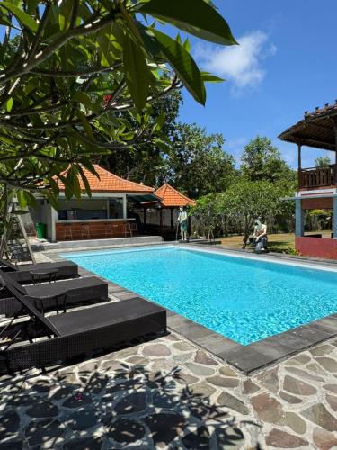 a swimming pool with two lounge chairs next to a building at Pecatu home stay in Uluwatu
