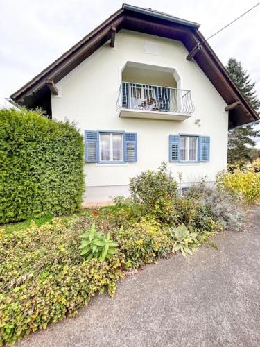 a white house with blue windows and a balcony at Luxuriöses Bauernhaus mit Garten und Parkplatz in Straß in Steiermark