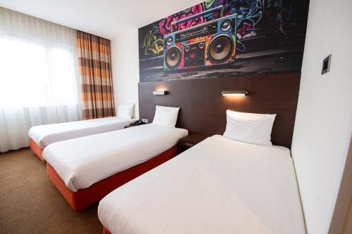 two beds in a hotel room with speakers on the wall at DeSilva Warszawa Piaseczno in Piaseczno