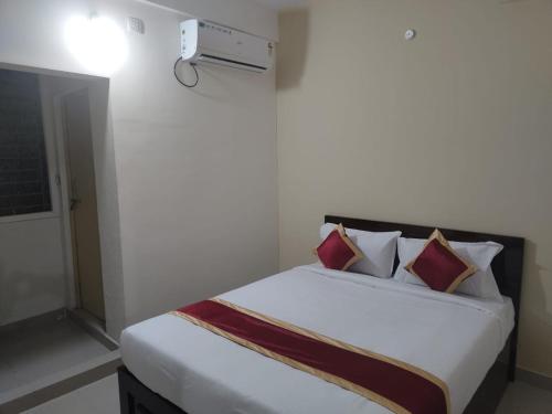 a bedroom with a bed with white sheets and red pillows at SS Suites in Bengaluru