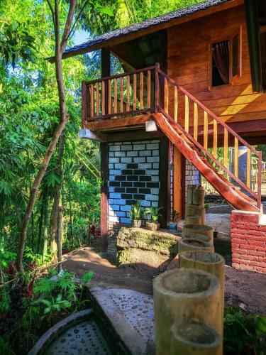 a house with a wooden staircase in front of it at Jonny's Places in Tetebatu