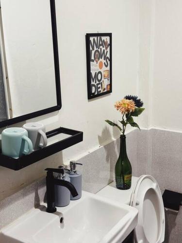 a bathroom with a white sink and a vase with a flower at Janatyy Guest House Suratthani in Suratthani