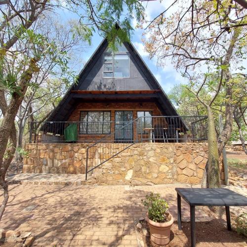 una casa con tetto di paglia e muro di pietra di Tranquil Nest a Rustenburg