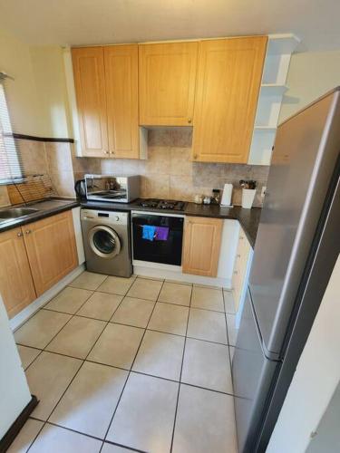 a kitchen with wooden cabinets and a stainless steel refrigerator at 2d - 50 No load shedding - 2 bedroom in Centurion