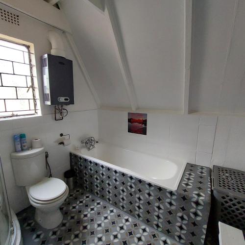 bagno con vasca, servizi igienici e TV di Tranquil Nest a Rustenburg