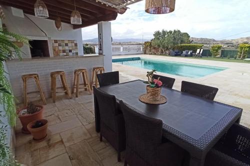 a dining table and chairs in a patio with a swimming pool at Casa rural Las Golondrinas in Huércal-Overa