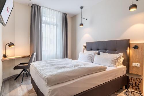 a bedroom with a bed and a desk and a window at Hotel Esplanade Dortmund in Dortmund