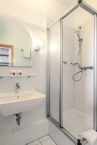 a white bathroom with a shower and a sink at Hotel Esplanade Dortmund in Dortmund