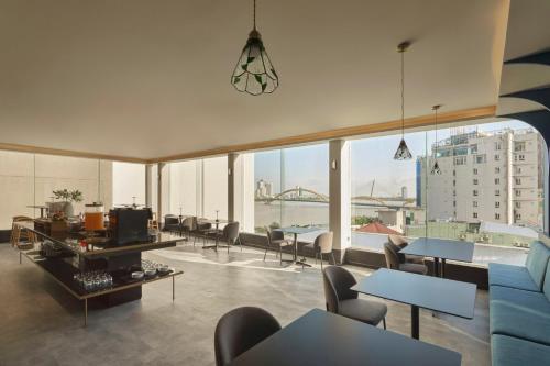 a living room with tables and chairs and a large window at M Village Hotel Da Nang Centre - Free Laundry and Kitchen in Da Nang