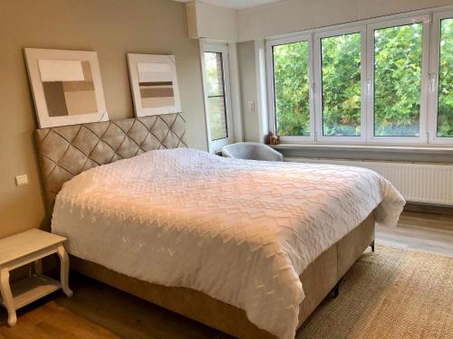 ein Schlafzimmer mit einem großen Bett und zwei Fenstern in der Unterkunft The Cozy Cottage in Eeklo