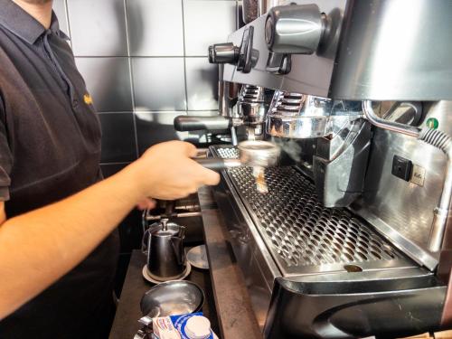 a man operating a coffee machine in a kitchen at B&B Sweet Sleep in Naples