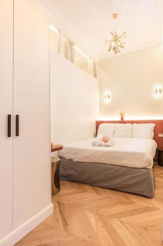 - une chambre avec un lit aux murs blancs et du parquet dans l'établissement Luxe Rouvet I Netflix I Calme, à Paris