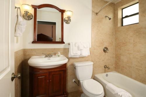 a bathroom with a toilet and a sink and a tub at Brand Plaza Hotel in Glendale
