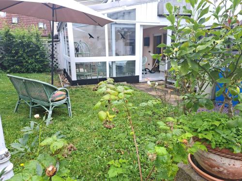 a garden with a chair and an umbrella and some plants at Einzelzimmer am Main in Knetzgau