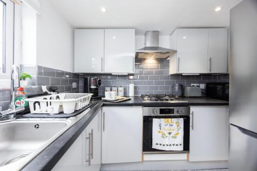 a kitchen with white cabinets and a stove top oven at Quick Access to London City, Self Check-in! in London