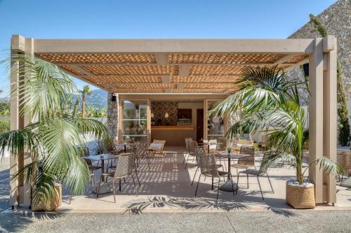 a patio with tables and chairs and palm trees at Utopia Blu Hotel in Tigaki