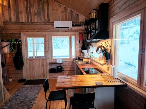 a kitchen with a wooden counter and a wooden table at Lapland Riverside Cabin, Äkäsjoki Hideaway - Riverview, Traditional Sauna, Avanto, WiFi, Ski, Ylläs in Äkäsjoensuu