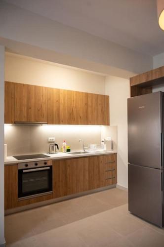 a kitchen with wooden cabinets and a stainless steel refrigerator at LYAN Cozy Apartment by HOME SH in Nafplio