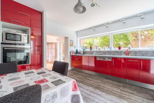 une cuisine avec des armoires rouges et une table avec des chaises dans l'établissement Apt T5 rénové avec bureau jardin et parking en centre ville, à Toulouse
