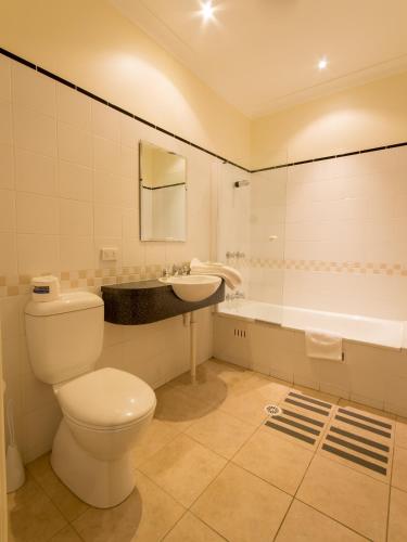 a bathroom with a toilet and a sink and a tub at Royal Hotel in Springwood