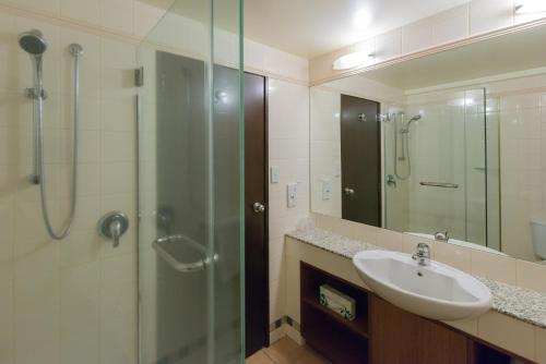 a bathroom with a sink and a shower with a glass door at Millennium Hotel & Resort Manuels Taupo in Taupo