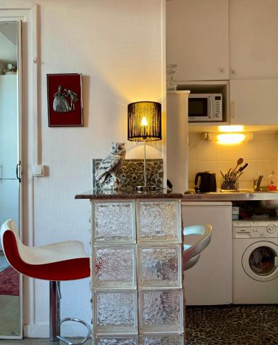 une cuisine avec un comptoir, une chaise rouge et une lampe dans l'établissement Studio chic Paris Tour Eiffel Near Eiffel tower 7th floor, à Paris