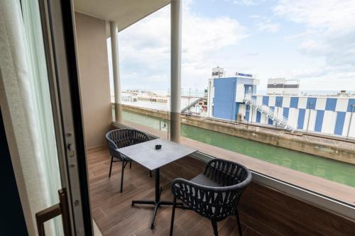 a balcony with two chairs and a table and a large window at Visionair Suites & SPA-Room Only e Honesty Bar in Senigallia
