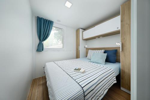 a small bedroom with a bed with a window at Albatross Mobile Homes on Valamar Camping Lanterna in Poreč