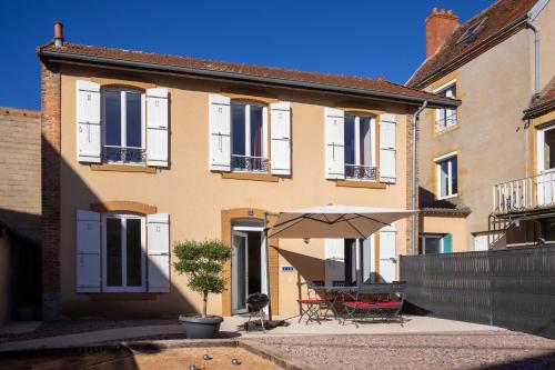a house with a table and an umbrella in front of it at La Maison du Parc in Digoin
