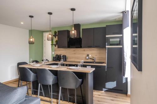 a kitchen with black cabinets and a bar with stools at La Maison du Parc in Digoin