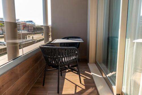 a balcony with a table and two chairs and a window at Visionair Suites & SPA-Room Only e Honesty Bar in Senigallia