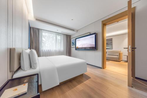 a bedroom with a white bed and a flat screen tv at Atour Hotel Beijing Temple of Heaven East Gate Longtan Park in Beijing