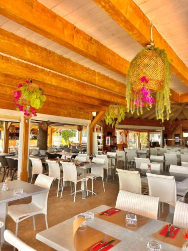 un restaurant avec des tables et des chaises blanches et des plafonds en bois dans l'établissement Résidence San Pellegrino, à Folelli