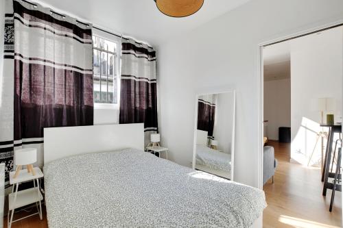 a white bedroom with a bed and a mirror at Centre Vincennes - Logement cosy in Vincennes