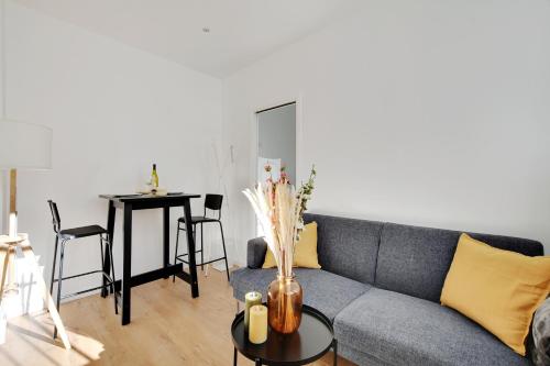 a living room with a couch and a table at Centre Vincennes - Logement cosy in Vincennes