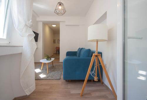 a living room with a blue couch and a lamp at D&A Amphitheatre Apartments with free parking in Pula