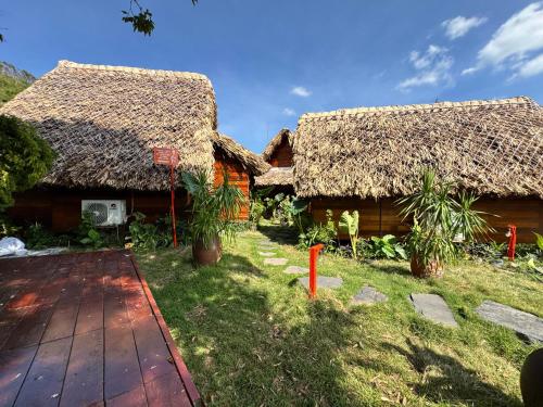 two thatched cottages with a grass roof at JoyStay in Cat Ba