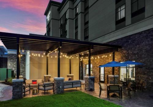 an outdoor patio with tables and chairs and umbrellas at Homewood Suites By Hilton Greensboro Wendover, Nc in Greensboro