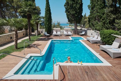 a woman is sitting in a swimming pool at Villa Diocletian's Palace in Supetar