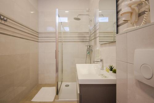 a white bathroom with a shower and a sink at D&A Amphitheatre Apartments with free parking in Pula