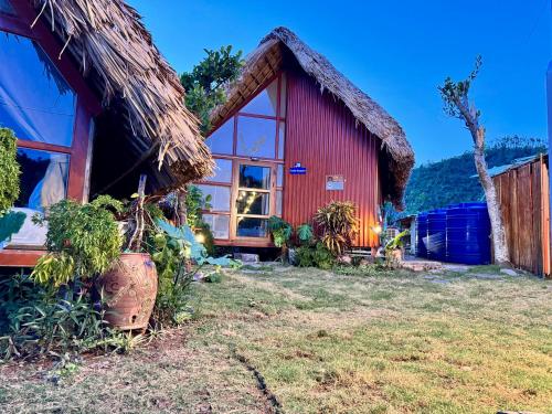 a small red house with a thatched roof at JoyStay in Cat Ba