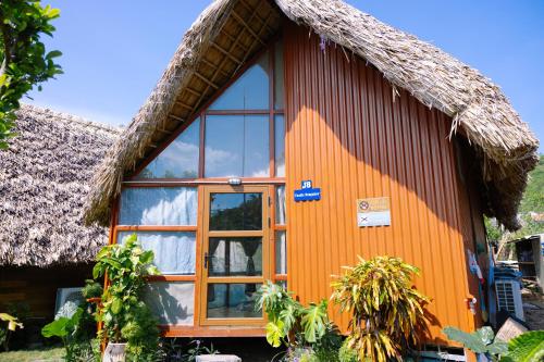 a small house with a thatched roof at JoyStay in Cat Ba