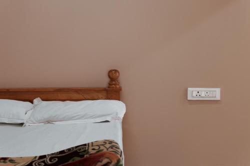 a bedroom with a bed and an alarm clock on the wall at Heath Cote in Ooty