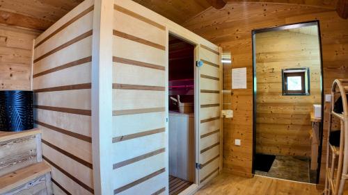 Cette chambre en bois dispose d'une porte dans une cabine. dans l'établissement Les Fermes de Manat gîte romantique avec piscine balnéo et sauna, à Luriecq