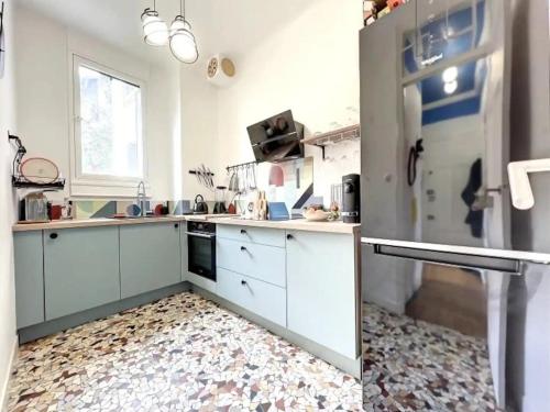  La cuisine est équipée de placards blancs et d'un réfrigérateur. dans l'établissement Le point carré - Smart & Cosy - Centre-Ville, à Troyes