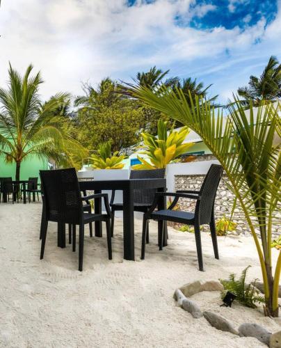 a black table and chairs on the beach at Blue Coral Vashafaru Maldives in Vashafaru
