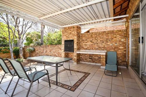 a patio with a table and chairs and a brick wall at Secured Home in Centurion