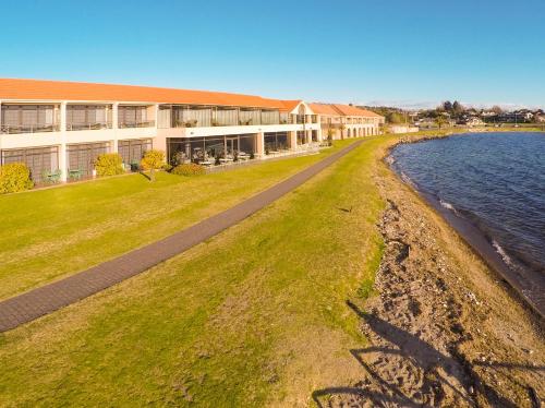 a building on the shore of a body of water at Millennium Hotel & Resort Manuels Taupo in Taupo